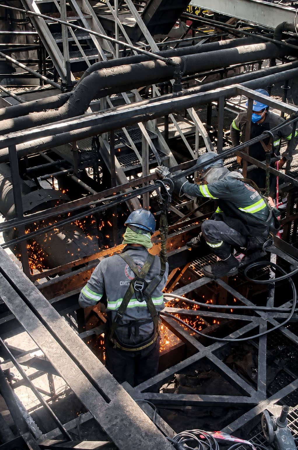 Equipe executando corte e solda em estrutura industrial